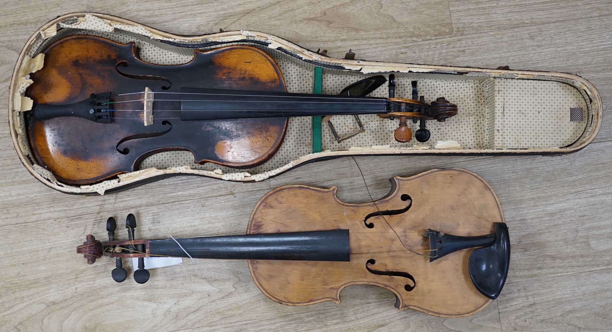 Two early 20th century violins, one in the remains of a case, both for restoration, length of bodies, 35.5cm and 36cm